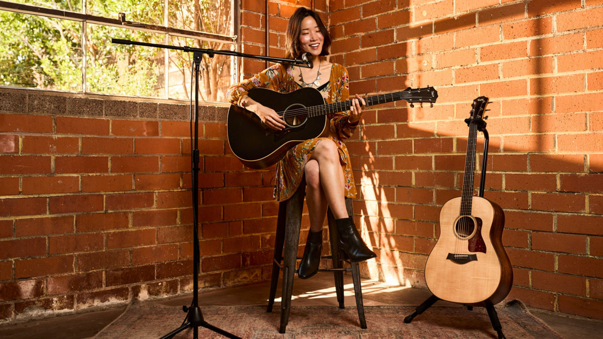 woman playing Taylor American Dream acoustic guitar at open mic show