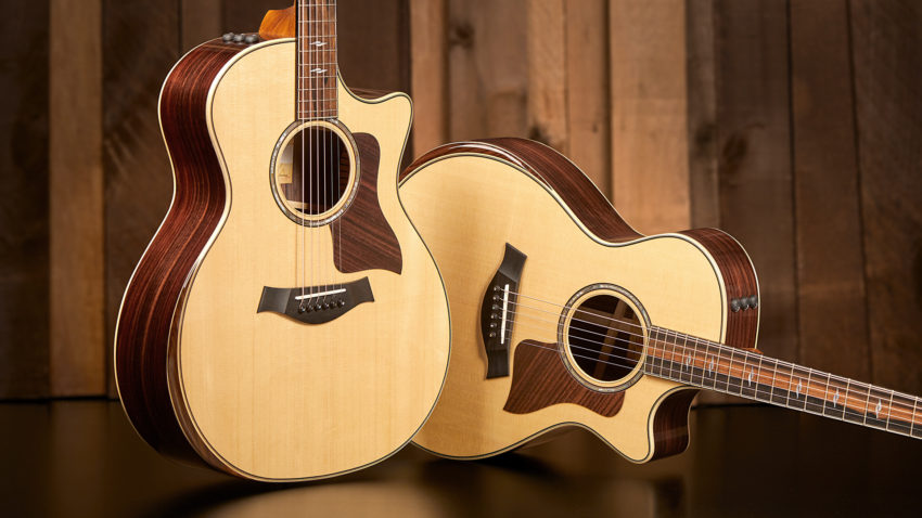 two taylor acoustic guitars, one standing and one leaning, facing front to display body shapes