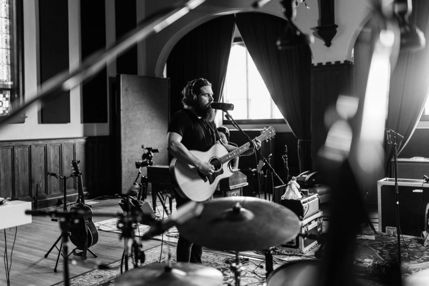 Manchester Orchestra singer and guitarist Andy Hull prepares to play in black and white photo