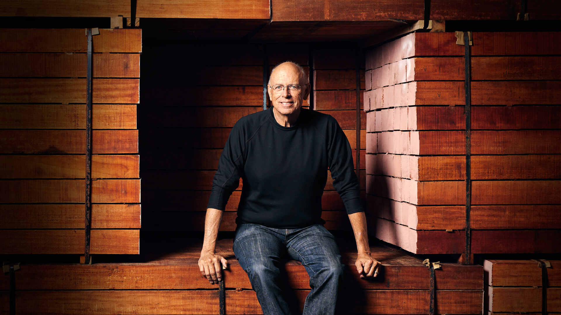 Bob Taylor seated on stack of mahogany wood