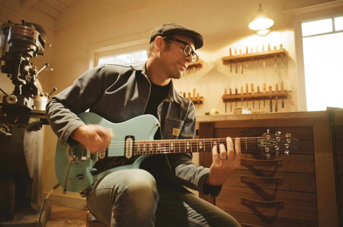 Guitar designer Andy Powers plays a light blue Powers Electric guitar in a luthier's workshop