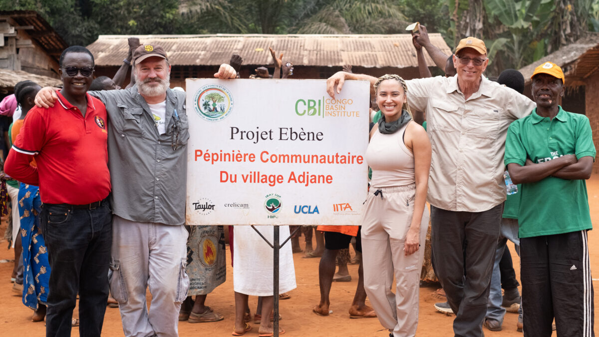 Header image of staff from Taylor Guitars and the Crelicam mill in Cameroon standing around a sign for the Ebony Project in French